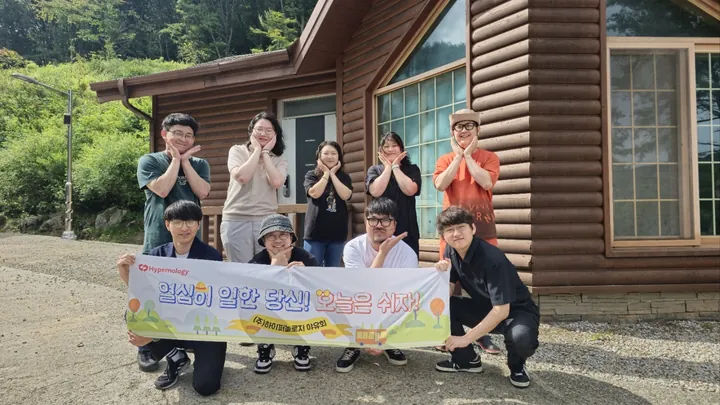 야유회 현수막을 들고 통나무집 앞에 모인 임직원