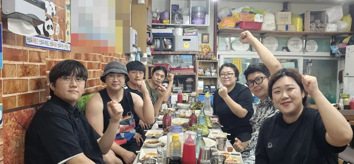 식당에서 함께 주먹을 쥐고 웃는 임직원